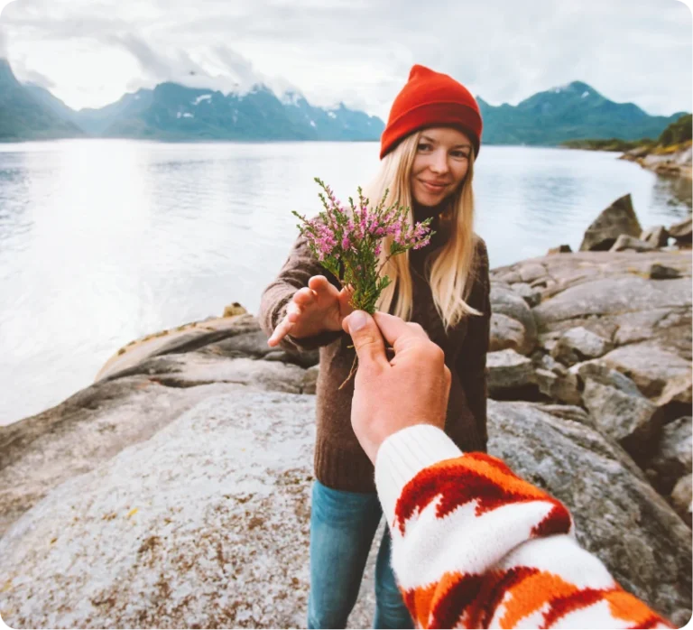 Photo of a woman being handed a bouquet of flowers by a lake